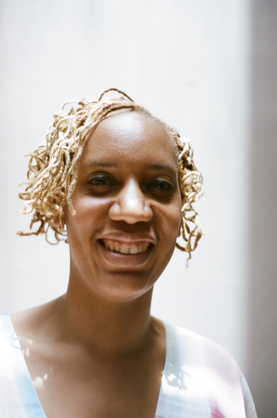 Photo portrait of young African woman smiling with blonde braids.